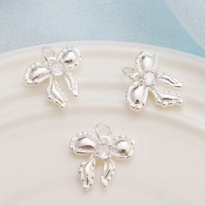 Detail shot of three silver bow pendants with cubic zirconia on white plate