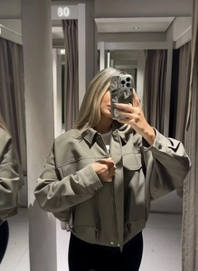 Dettagli della giacca in similpelle grigio-verde con colletto a rever e maxi tasche