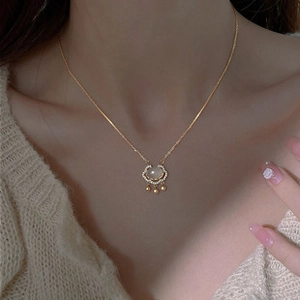 Close-up of gold Ruyi lock pendant with white jade stone and diamond-encrusted edges