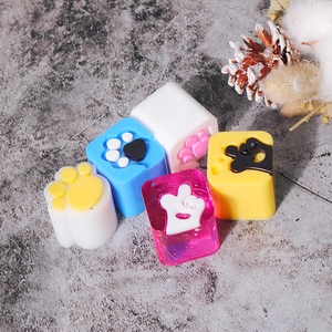 Detailed view of colorful 3D cat paw resin keycaps and molds on a stone surface