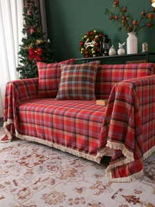 Detail of red plaid sofa cover with fringe and matching pillow in Christmas home setting
