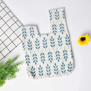Close-up of minimalist cotton linen wrist bag with blue leaf pattern on white canvas