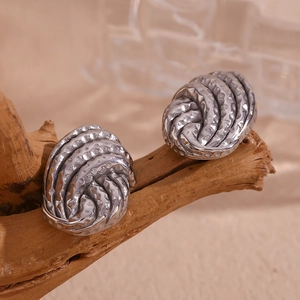 Detailed view of silver twisted knot earrings with hammered texture on natural wood