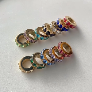 Macro view of colorful rhinestone-encrusted gold-plated spacer beads for DIY jewelry.