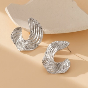 Silver C-shaped chunky earrings with textured wave surface on a minimalist stone base