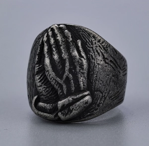 Close-up of vintage silver prayer hands relief on a stainless steel ring for men and women