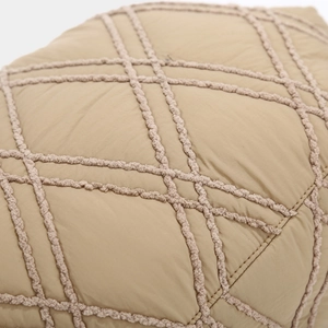 Macro shot of khaki quilted fabric with a diamond pattern and textured embroidery details