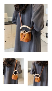Detail view of mini brown suede bucket bag with cream faux fur trim and leather strap