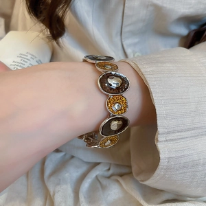 Close-up of enamel metal bracelet with irregular oval links in silver and amber tones