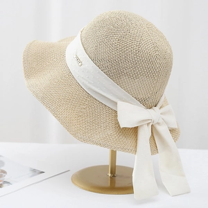 Cappello da sole in paglia con fiocco a pois bianchi su elegante supporto dorato