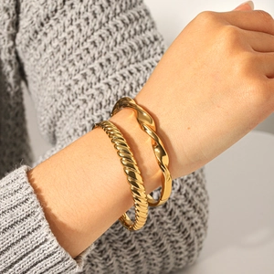 Détail de bracelets torsadés en acier inoxydable plaqué or 18 carats avec cœur brillant