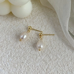Close-up of elegant baroque freshwater pearl drop earrings with golden stud detail