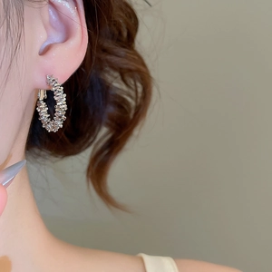 Close-up of irregular textured silver hoop earrings with intricate woven pattern on model