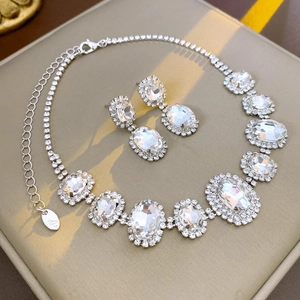 Macro view of silver-tone oval crystal pendant and matching drop earrings on velvet