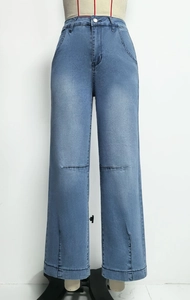 Détail du jean bleu clair à jambes larges avec fentes latérales et finitions délavées
