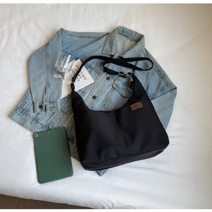Detail of black nylon tote bag with fashion leather patch beside a tablet and denim jacket