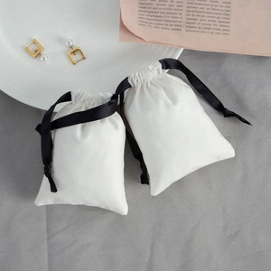 Close-up of small white cotton drawstring bags with black satin ribbons for jewelry