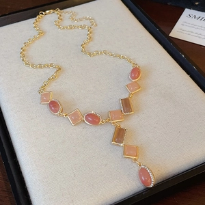 Detail of vintage Y-shaped necklace with pink and brown gems on a jewelry tray