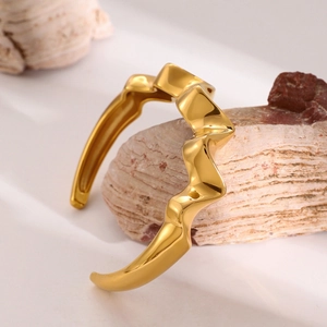 Close-up of 18k gold plated stainless steel wave bangle on natural stone base