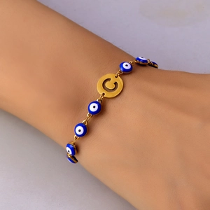 Detailed close-up of golden Evil Eye bracelet featuring blue beads and a letter C charm