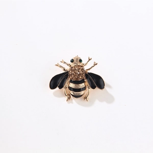 Vintage gold bee brooch with black enamel wings and brown rhinestones on white background