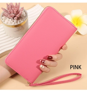 Detailed view of pink litchi grain leather wallet held by hand in lifestyle setting