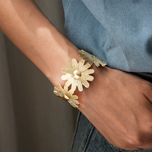 Détail d'un bracelet fleuri doré avec des pétales de marguerite en métal brossé fin