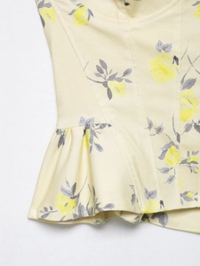 Detailed macro view of yellow floral poplin top featuring corset stitching and ruffled hem