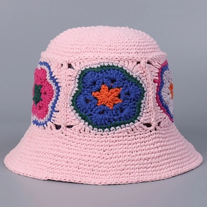 Macro detail of hand-crocheted pink fisherman hat featuring colorful floral knit patterns