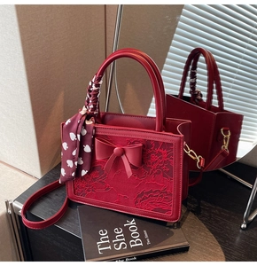 Detail of red bridal handbag featuring lace embroidery and silk scarf handle decoration