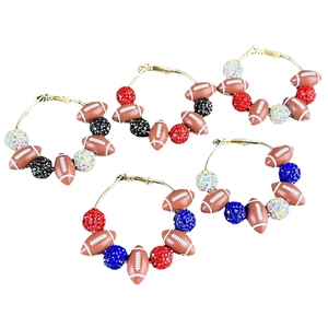 Détail de perles de rugby et boules de strass scintillantes sur créoles dorées