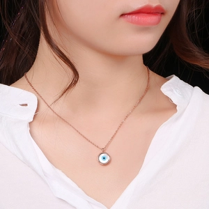 Close-up of a rose gold Evil Eye necklace with blue and white enamel on a female model