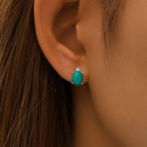 Detailed close-up of a silver earring featuring oval turquoise and a small zircon stud