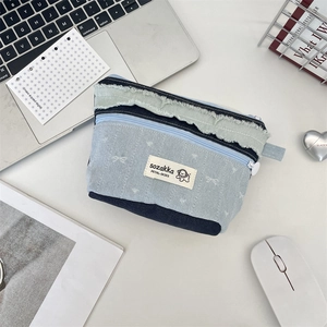 Detail der Denim-Kosmetiktasche mit Patchwork-Design und grünem Fransenrand-Saumdetail