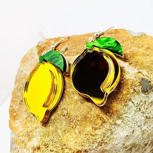 Yellow lemon shaped acrylic earrings with green leaf details on natural stone background
