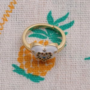 Macro shot of gold plated evil eye heart ring with colorful zircon on pineapple fabric