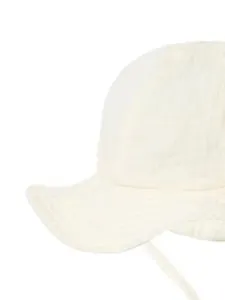 Close-up of white baby sun hat made of textured cotton muslin with wavy brim and tie string