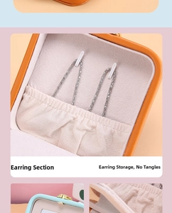 Detail of the orange leather jewelry box featuring ear stud hooks and a soft pouch