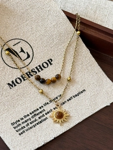 Detail of layered tiger eye stone necklace with sun pendant and linen storage pouch