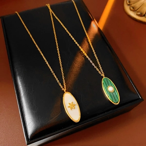 Detail of vintage sun oval pendants in gold finish with white and green stones