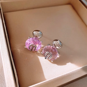 Macro shot of pink oval gemstone earrings with silver metallic M-letter logo detailing