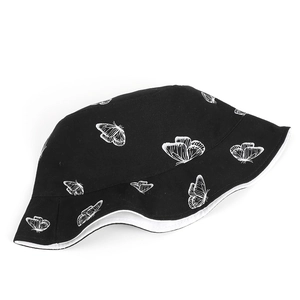 Détail d'un bob noir avec motifs de papillons blancs et bordure blanche renforcée de qualité