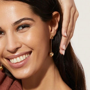 Close-up of 18K gold plated titanium steel earrings with long chain ball pendants