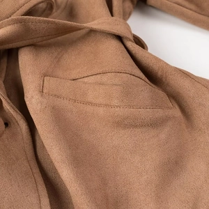 Detailed macro view of the brown faux suede jacket featuring belt strap and stitching