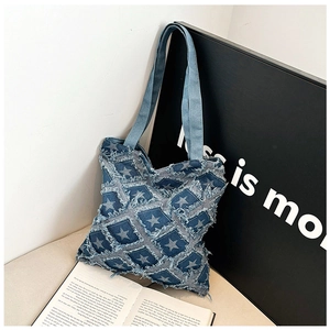 Detailed close-up of blue washed denim tote bag with textured frayed star patterns