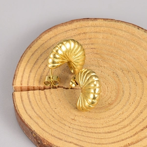 Macro detail of 18K gold plated fan shaped stud earrings with ribbed texture on wood