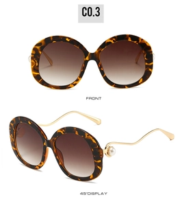 Detail of round leopard print sunglasses with gold metal temples and pearl accents