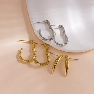 Polished 14K gold and silver bamboo style hoop earrings on minimalist display stand