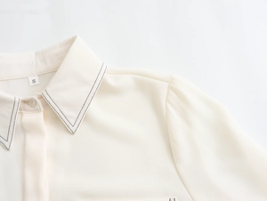 Close-up of cream shirt collar featuring black contrast stitching and size S label detail