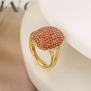Macro detail of gold plated ring with micro-set orange zircons on a minimal background